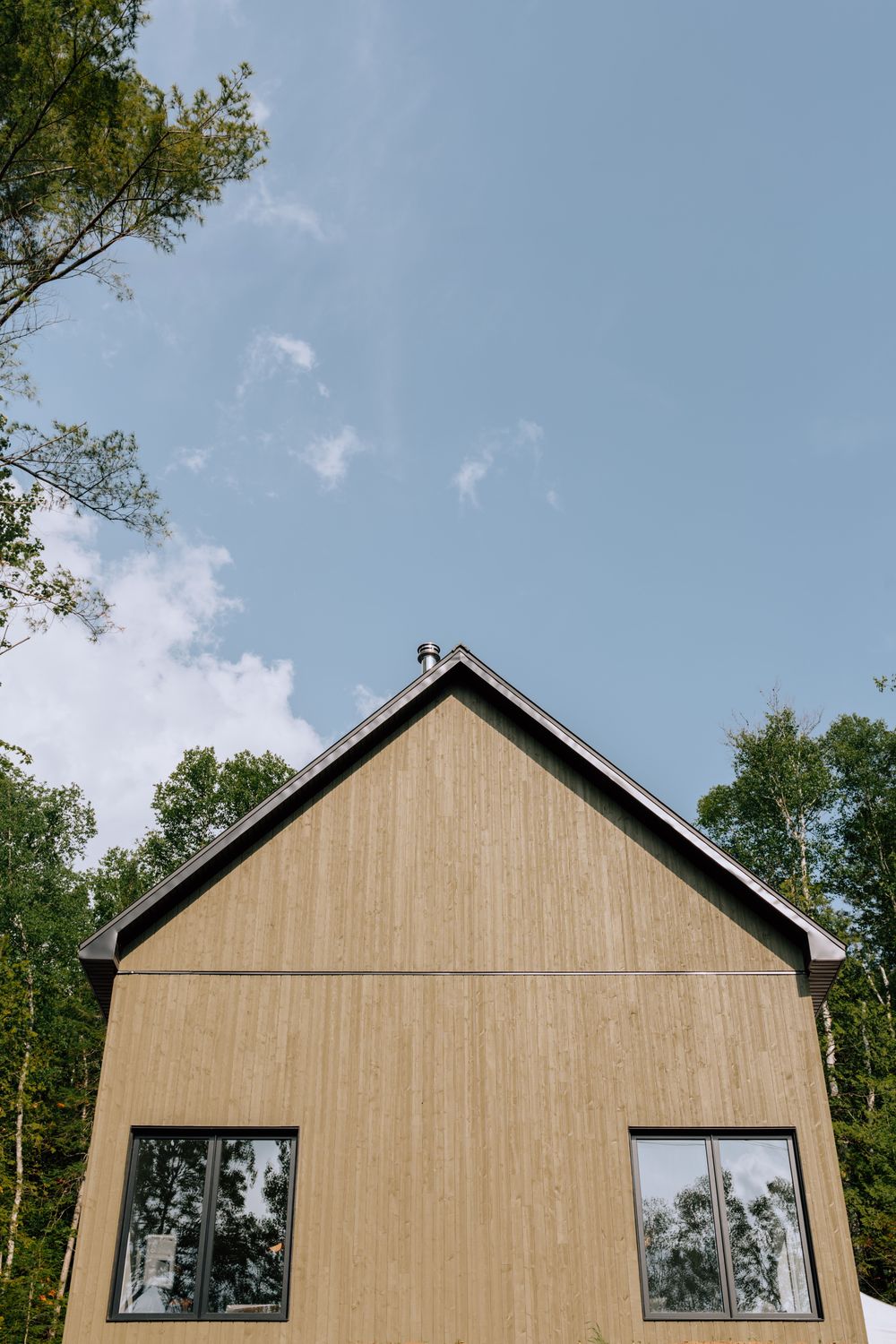 Pignon d'une maison Karborea, revêtement de bois clair et débord de toit noir