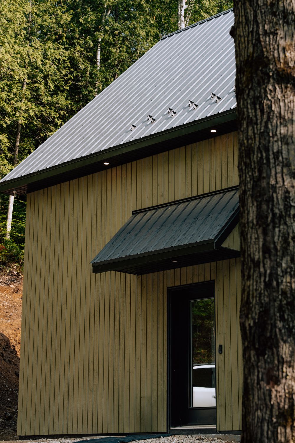 Entrée d'une maison Karborea, auvent en acier et revêtement de bois vertical