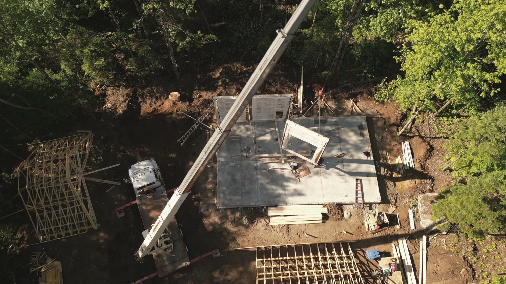 Vue aérienne d&rsquo;un chantier Karborea&nbsp;: une grue dépose un module préfabriqué sur la dalle.